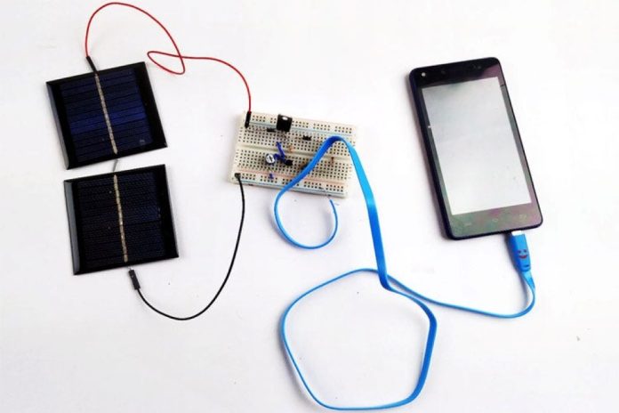 DIY solar-powered phone charger made from recycled materials, showing a small solar panel connected to a smartphone