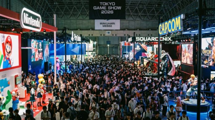 Thousands of visitors walk through the crowded exhibition halls of Makuhari Messe during Tokyo Game Show 2026, with large gaming booths and colorful displays from major publishers on either side